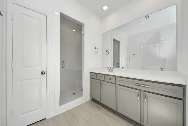 a bathroom with a granite countertop sink two mirror and shower
