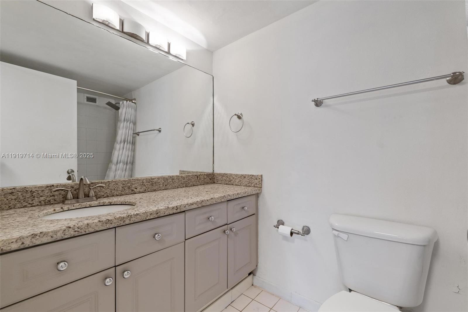 2301 Collins Avenue, Unit 802 Miami Beach, FL 33139 - Photo 24 of 26 a bathroom with a granite countertop sink a toilet and a mirror
