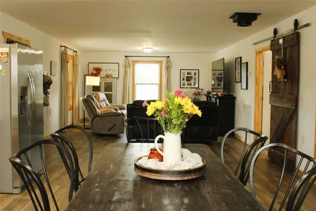a living room with furniture potted plant kitchen view and a window