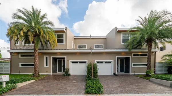 a front view of a house with a yard and palm trees