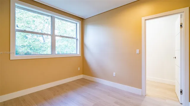 a view of a hallway with wooden floor and a bathroom
