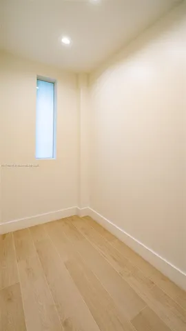 a view of a hallway with wooden floor and a bathroom