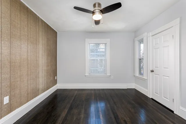 an empty room with wooden floor fan and windows