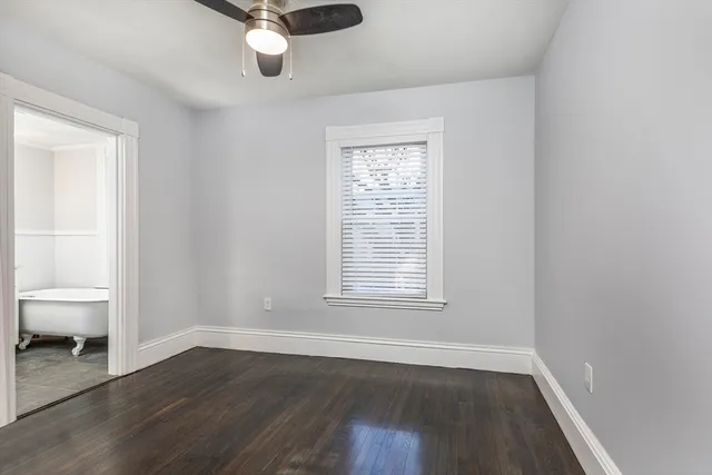 an empty room with wooden floor cabinet and windows