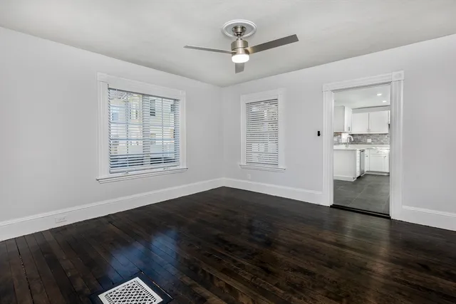 a view of empty room with wooden floor and ceiling fan