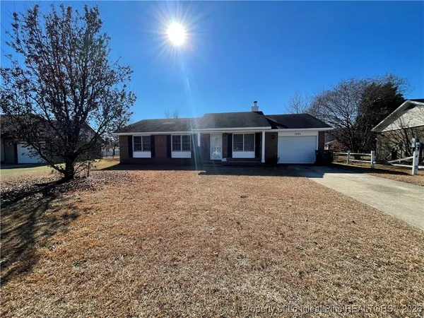a front view of a house with a yard covered with snow and trees