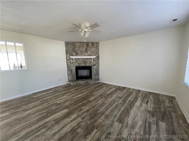 an empty room with wooden floor fireplace and windows