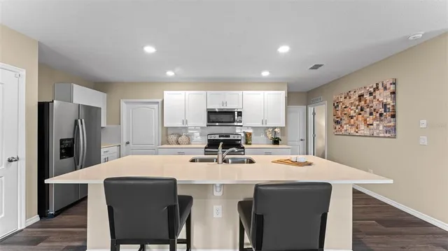 a kitchen with stainless steel appliances a kitchen island hardwood floor sink stove refrigerator and wooden cabinets