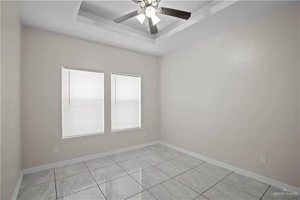an empty room with windows and chandelier fan