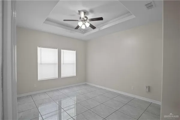 an empty room with chandelier fan and windows