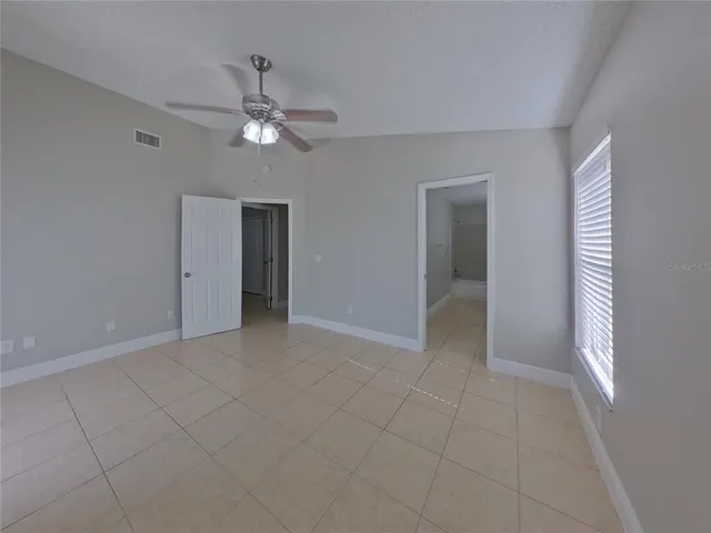 a view of an empty room with a ceiling fan and window