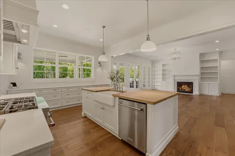 an empty room with wooden floor chandelier and windows