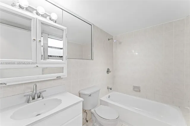 a bathroom with a bathtub shower sink vanity mirror and toilet