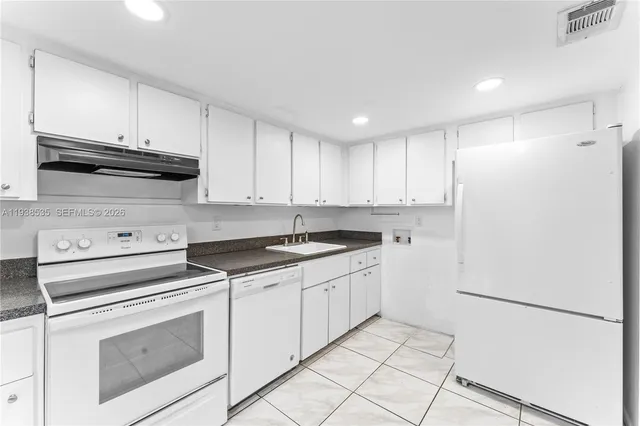 a kitchen with granite countertop white cabinets and white appliances