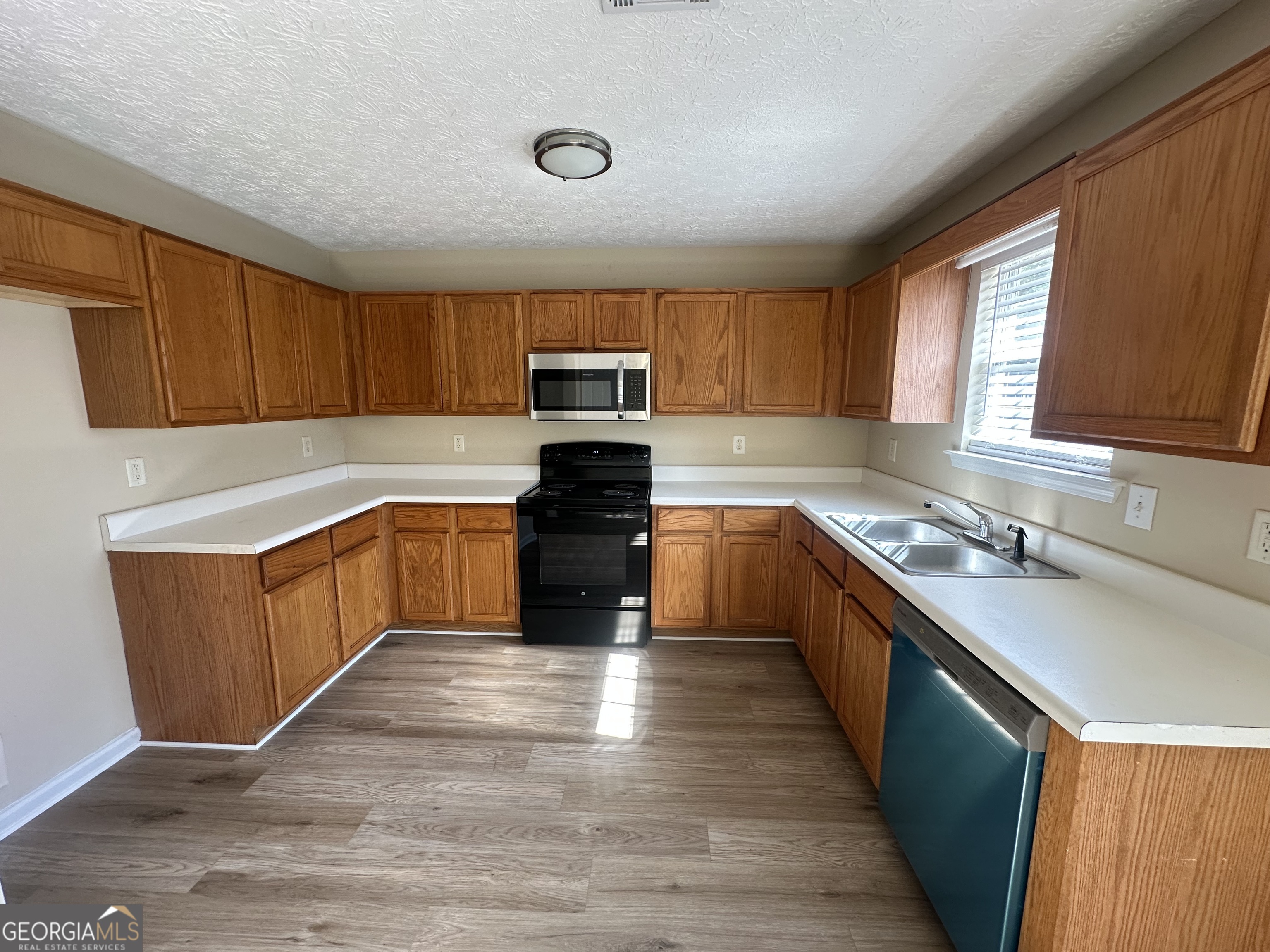 3860 Cedar Rock Road Woodbury, GA 30293 - Photo 6 of 14 a large kitchen with a stove top oven a sink dishwasher and a refrigerator with wooden cabinets
