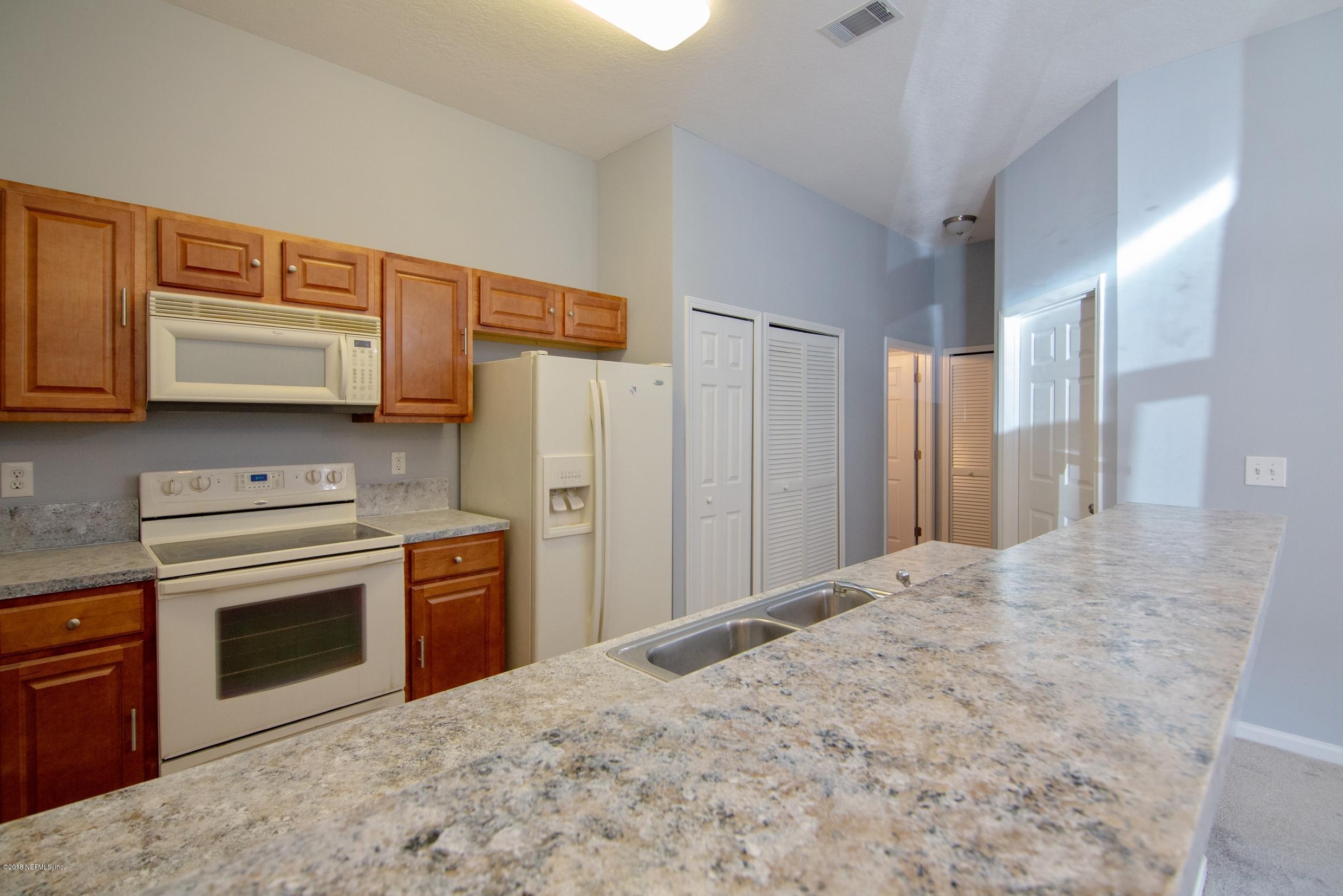 7920 Merrill Road, Unit 605 Jacksonville, FL 32277 - Photo 8 of 24 a kitchen with stainless steel appliances granite countertop a stove a refrigerator and a microwave with cabinets