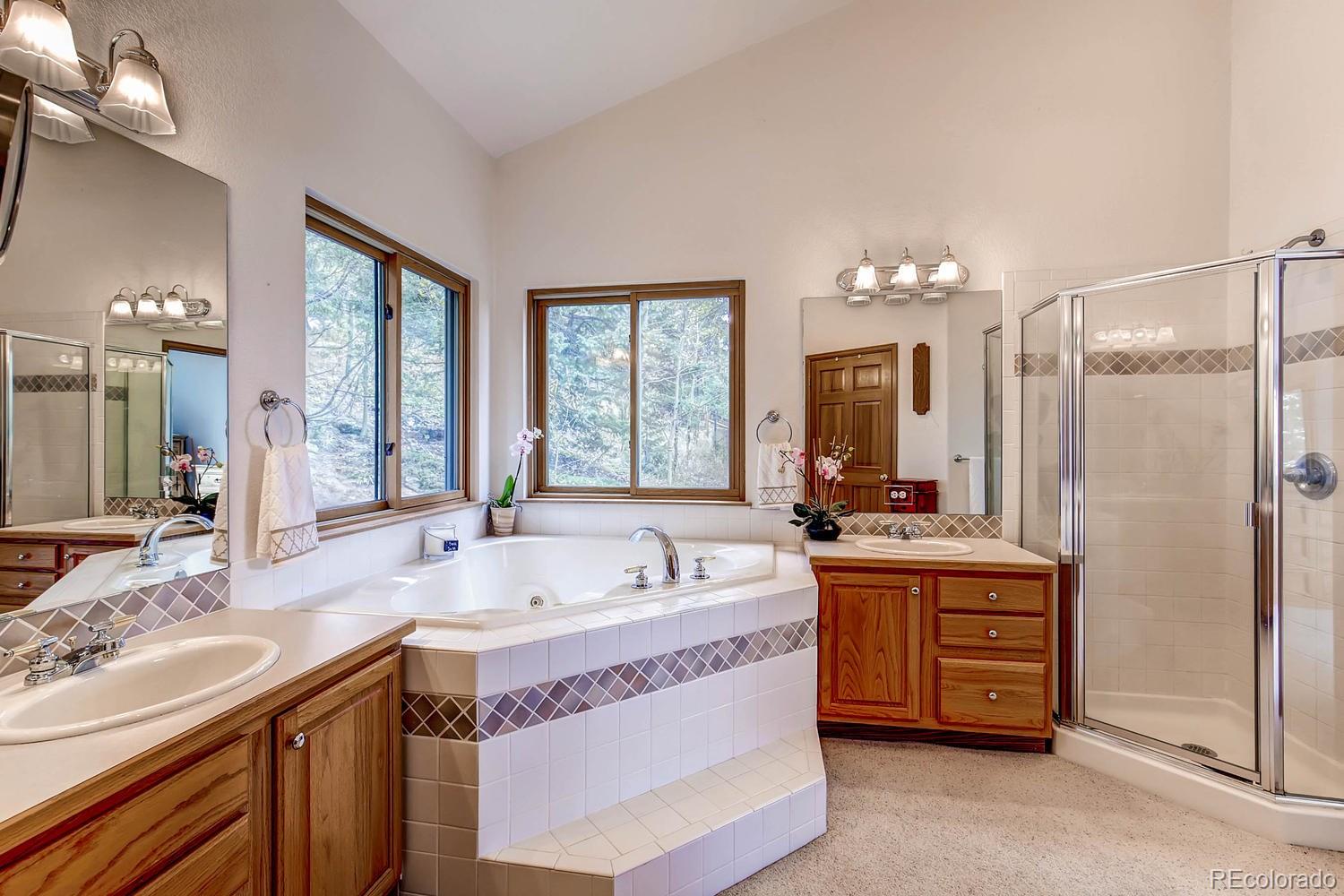 11760 Baca Road Conifer, CO 80433 - Photo 15 of 24 a spacious bathroom with a tub a double vanity sink a large mirror and a shower