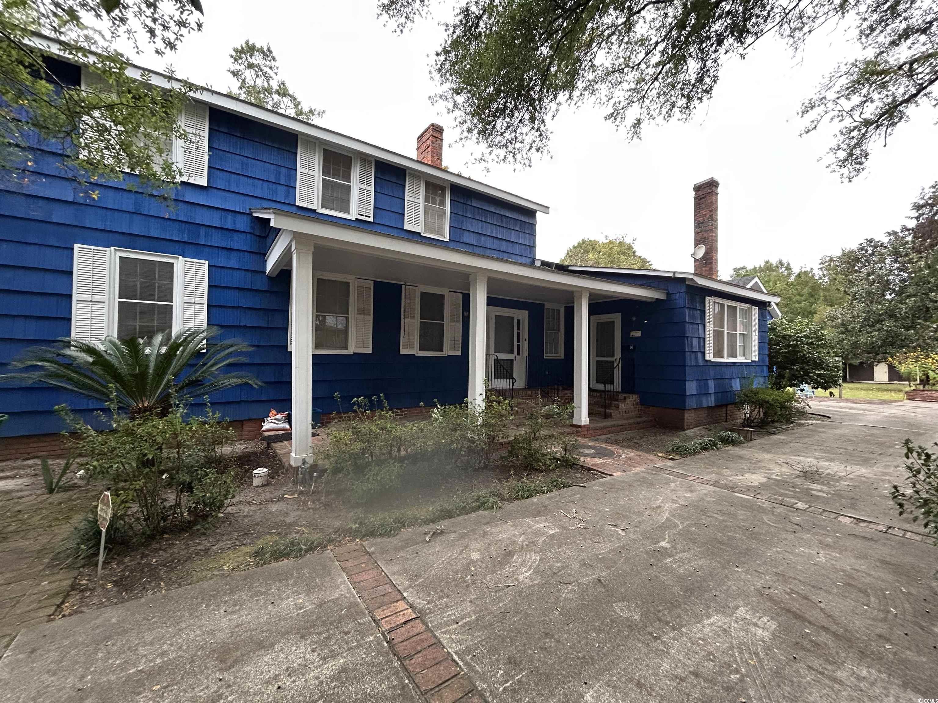 View of front of property featuring a chimney and a porch