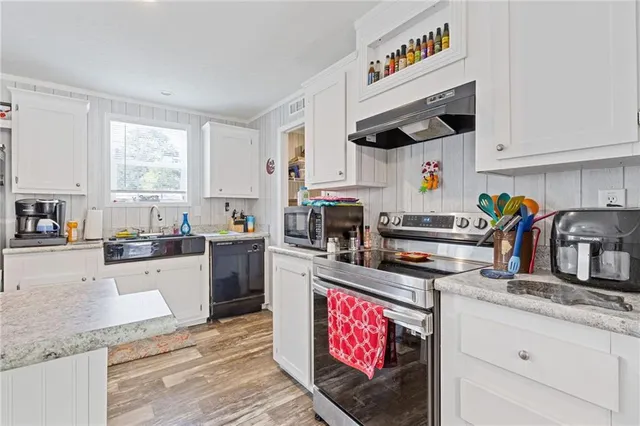 a kitchen with kitchen island granite countertop a sink cabinets stainless steel appliances and a window