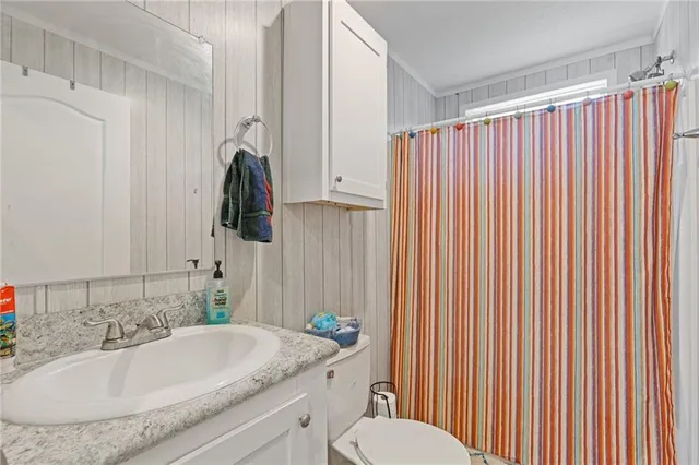 a bathroom with a granite countertop sink and a mirror with toilet