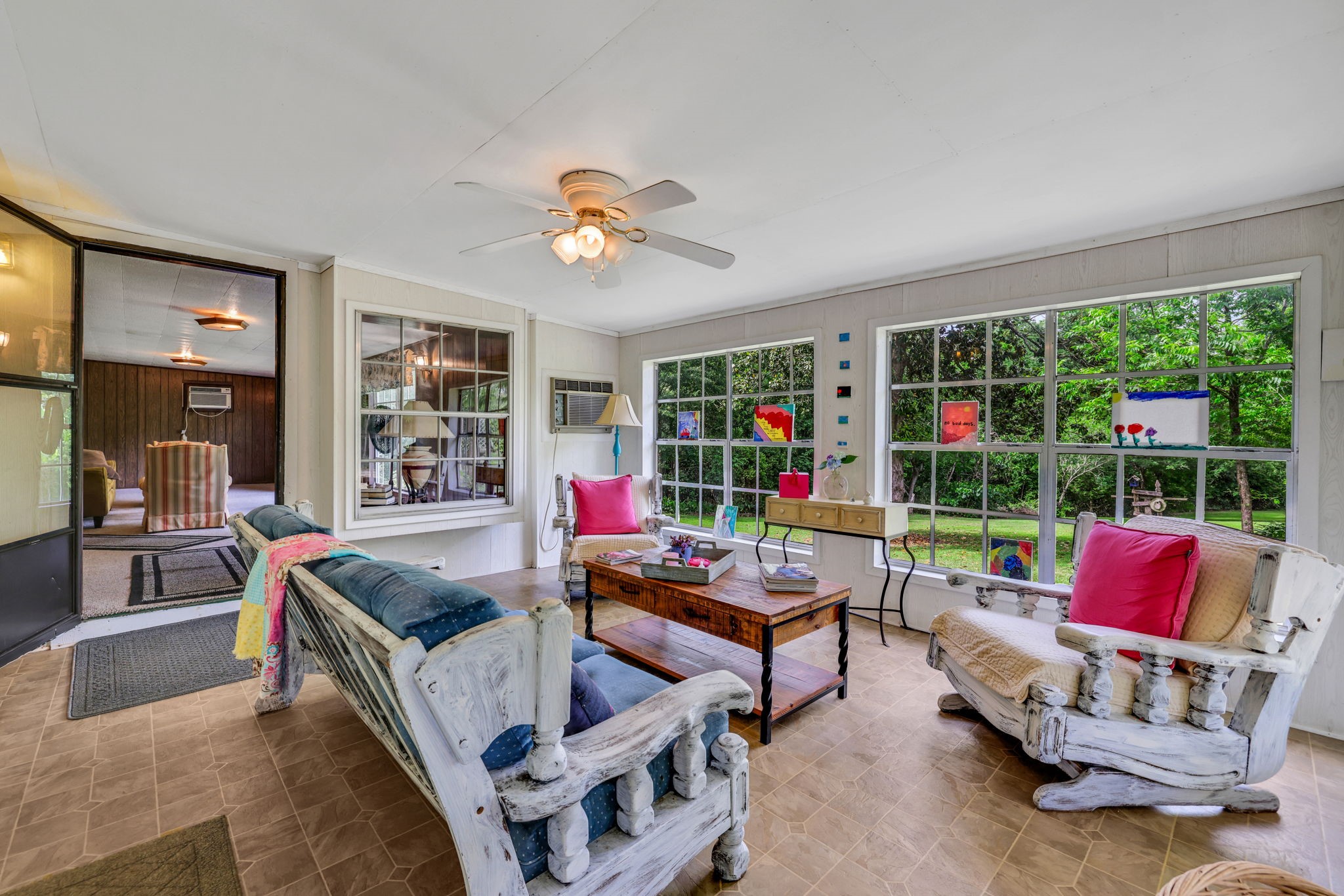 Bright and inviting sunroom featuring oversized windows, cozy seating, and views of the lush greenery outside—perfect for morning coffee or afternoon reading.