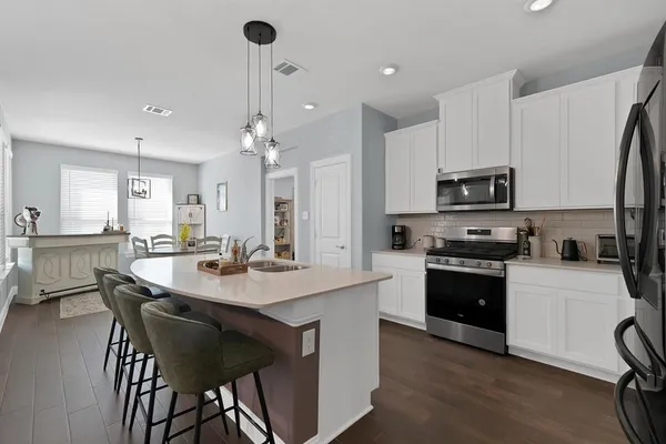 a kitchen with appliances a sink and chairs