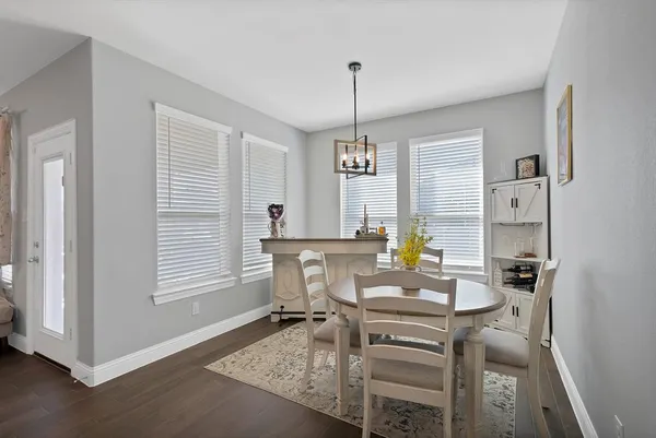 a kitchen with a sink dishwasher a stove a dining table and chairs with wooden floor