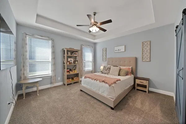 a bedroom with a bed a dresser and a large window