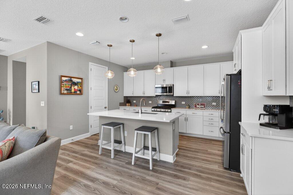 12 Wards Ravine Way St. Johns, FL 32259 - Photo 29 of 73 a kitchen with stainless steel appliances kitchen island granite countertop a refrigerator a stove a sink dishwasher and white cabinets with wooden floor