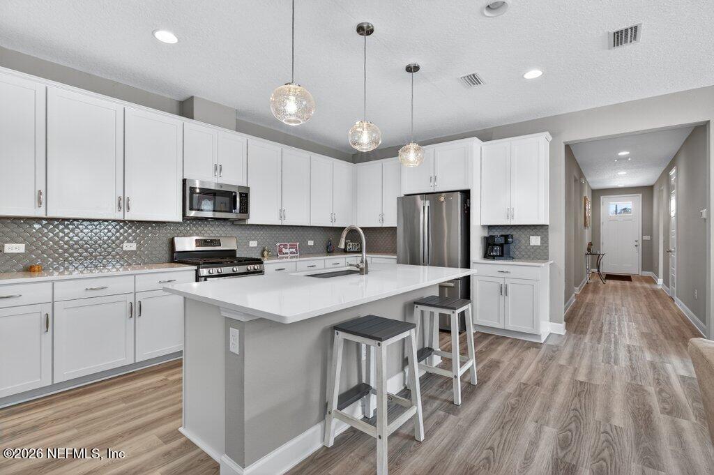 12 Wards Ravine Way St. Johns, FL 32259 - Photo 34 of 73 a kitchen with stainless steel appliances granite countertop a stove refrigerator a microwave oven a sink a dining table and chairs with wooden floor