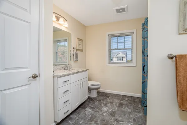 a bathroom with a granite countertop toilet a sink and a mirror