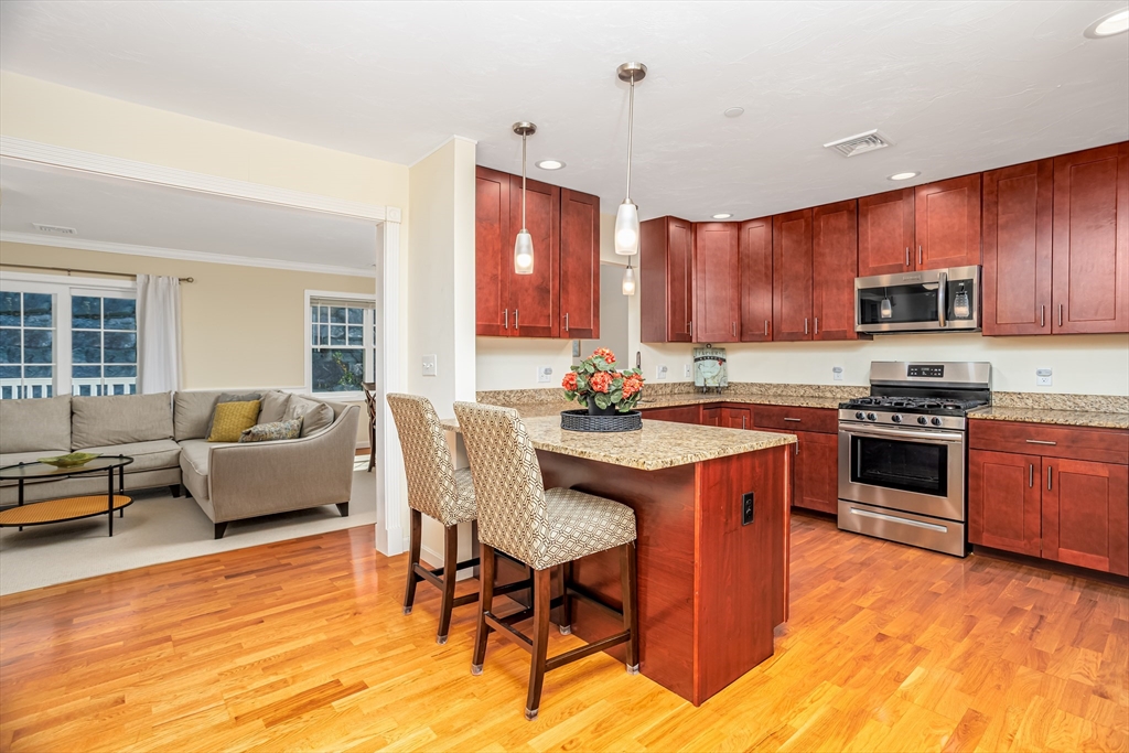1221 Hazelwood Way, Unit 1221 Clinton, MA 01510 - Photo 3 of 42 a kitchen with stainless steel appliances granite countertop a stove a sink dishwasher a dining table and chairs with wooden floor