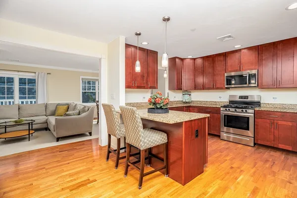 a kitchen with stainless steel appliances granite countertop a stove a sink dishwasher a dining table and chairs with wooden floor