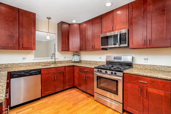 a kitchen with stainless steel appliances granite countertop wooden cabinets stove top oven and sink