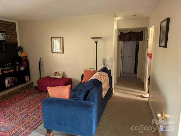 a living room with furniture a flat screen tv and a refrigerator