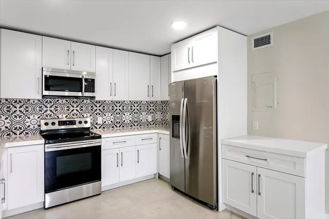 a kitchen with white cabinets and stainless steel appliances