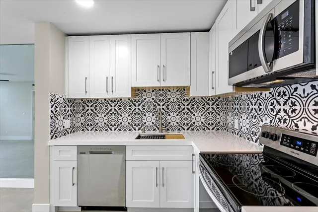 a kitchen with granite countertop white cabinets and black appliances
