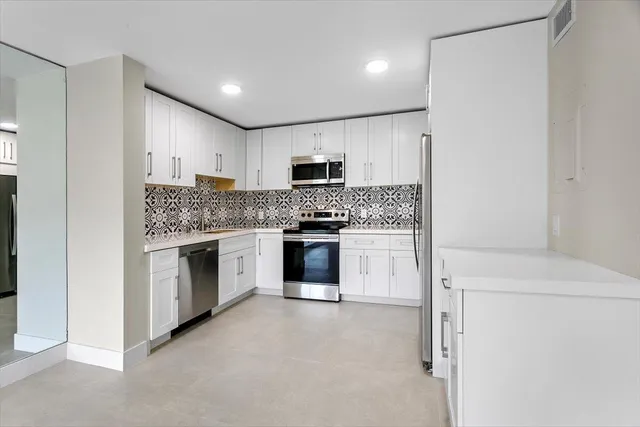 a kitchen with granite countertop white cabinets and stainless steel appliances