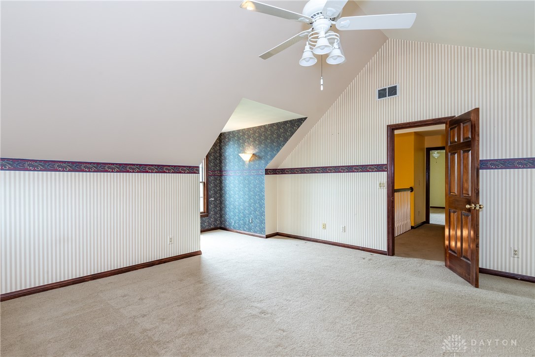 9981 Ridge Acres Lane Englewood, OH 45322 - Photo 35 of 73 This spacious bedroom offers comfortable carpeting and a unique sloped ceiling design.