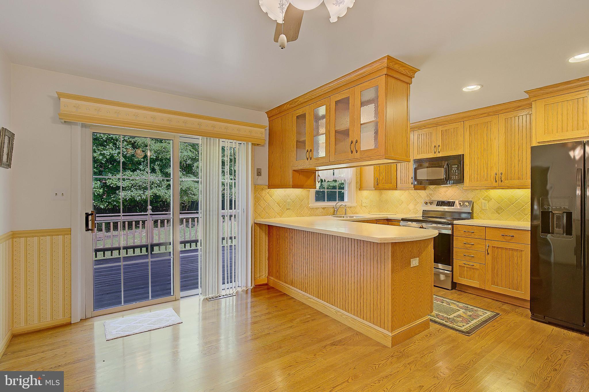 1750 Timber Court Huntingtown, MD 20639 - Photo 21 of 57 a kitchen with stainless steel appliances granite countertop a refrigerator a stove a sink and a dining table with wooden cabinet