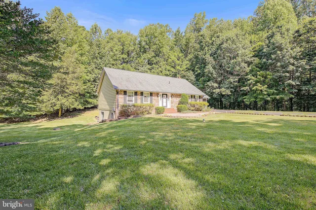 a house with huge green field with trees in the background
