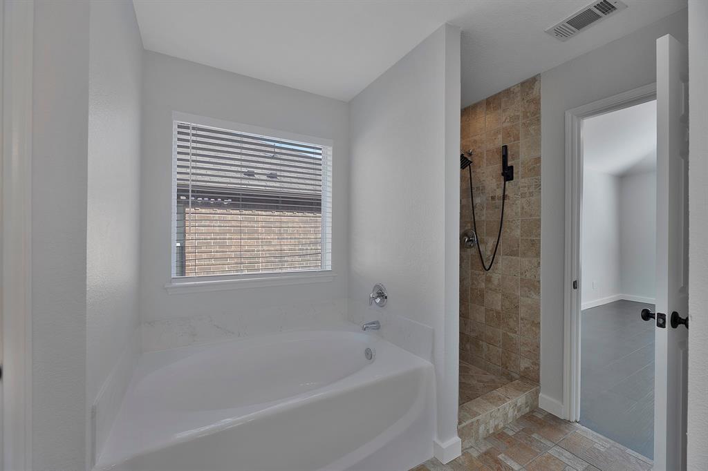 605 Clearbrook Street Azle, TX 76020 - Photo 18 of 33 Soaking tub with a white finish, tile surround, and window with blinds
