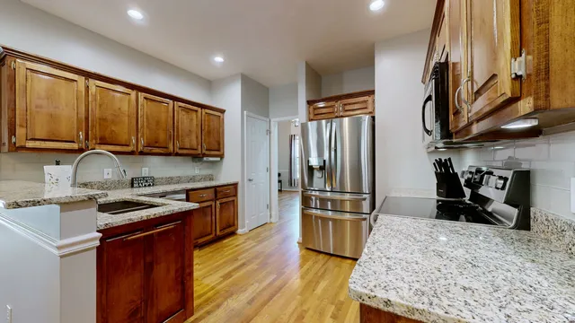 a kitchen with stainless steel appliances granite countertop a refrigerator a stove top oven a sink and dishwasher