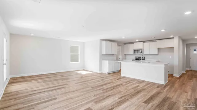 a view of a kitchen with white cabinets stainless steel appliances and window