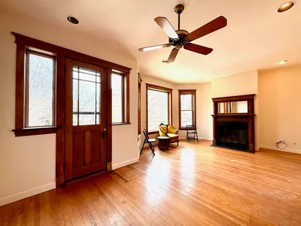 a view of a livingroom with furniture hardwood floor a ceiling fan and windows