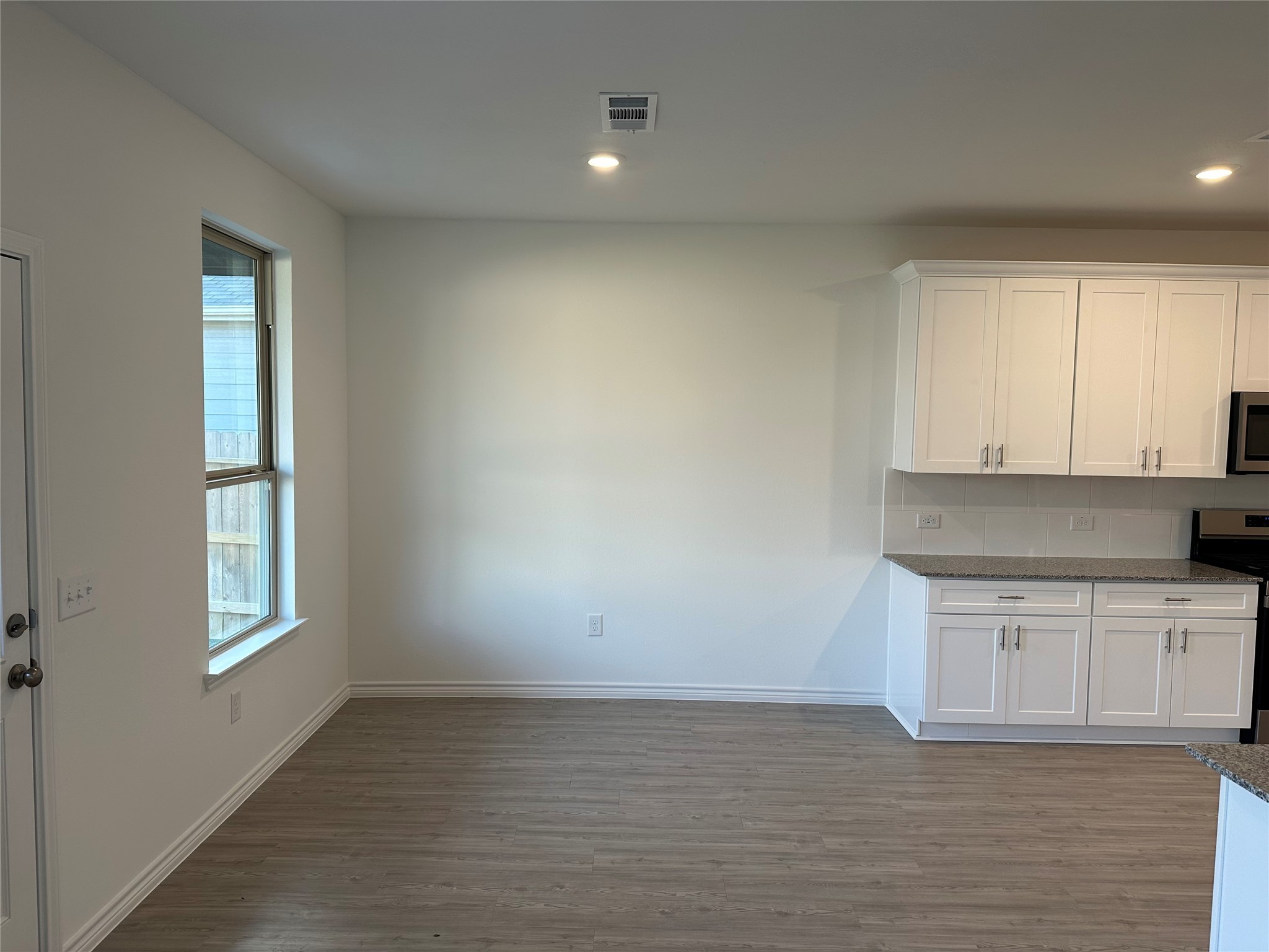 15214 Canyon Rapids Road Conroe, TX 77302 - Photo 4 of 22 a kitchen with granite countertop white cabinets and window