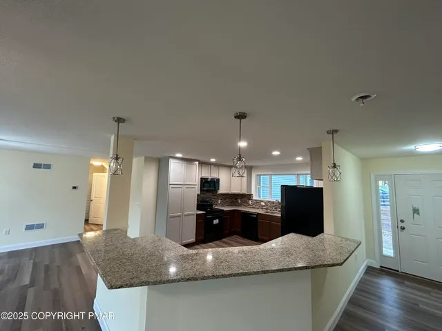 a kitchen with kitchen island granite countertop wooden cabinets and a sink