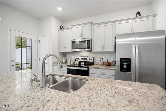 a kitchen with stainless steel appliances granite countertop a refrigerator a stove a sink and a microwave