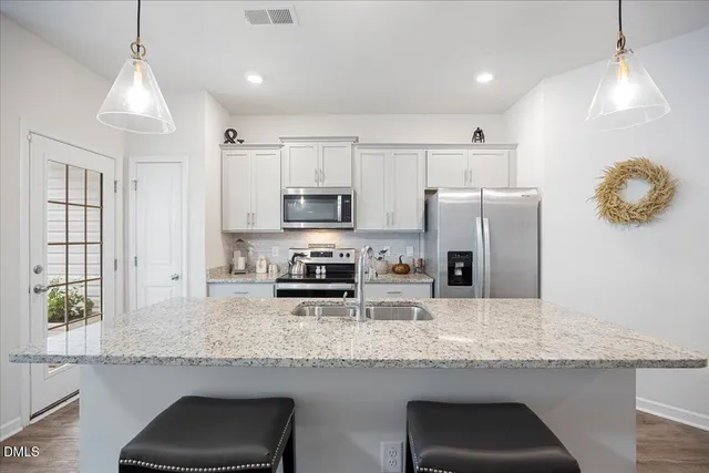 a kitchen with granite countertop a sink a counter space appliances and cabinets