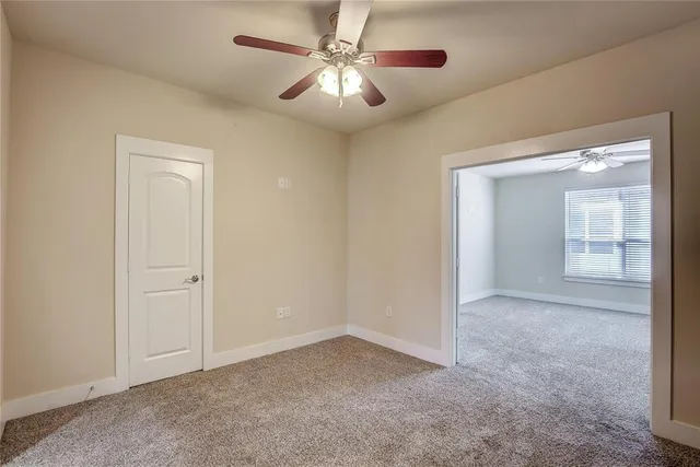 an empty room with a ceiling fan and a window